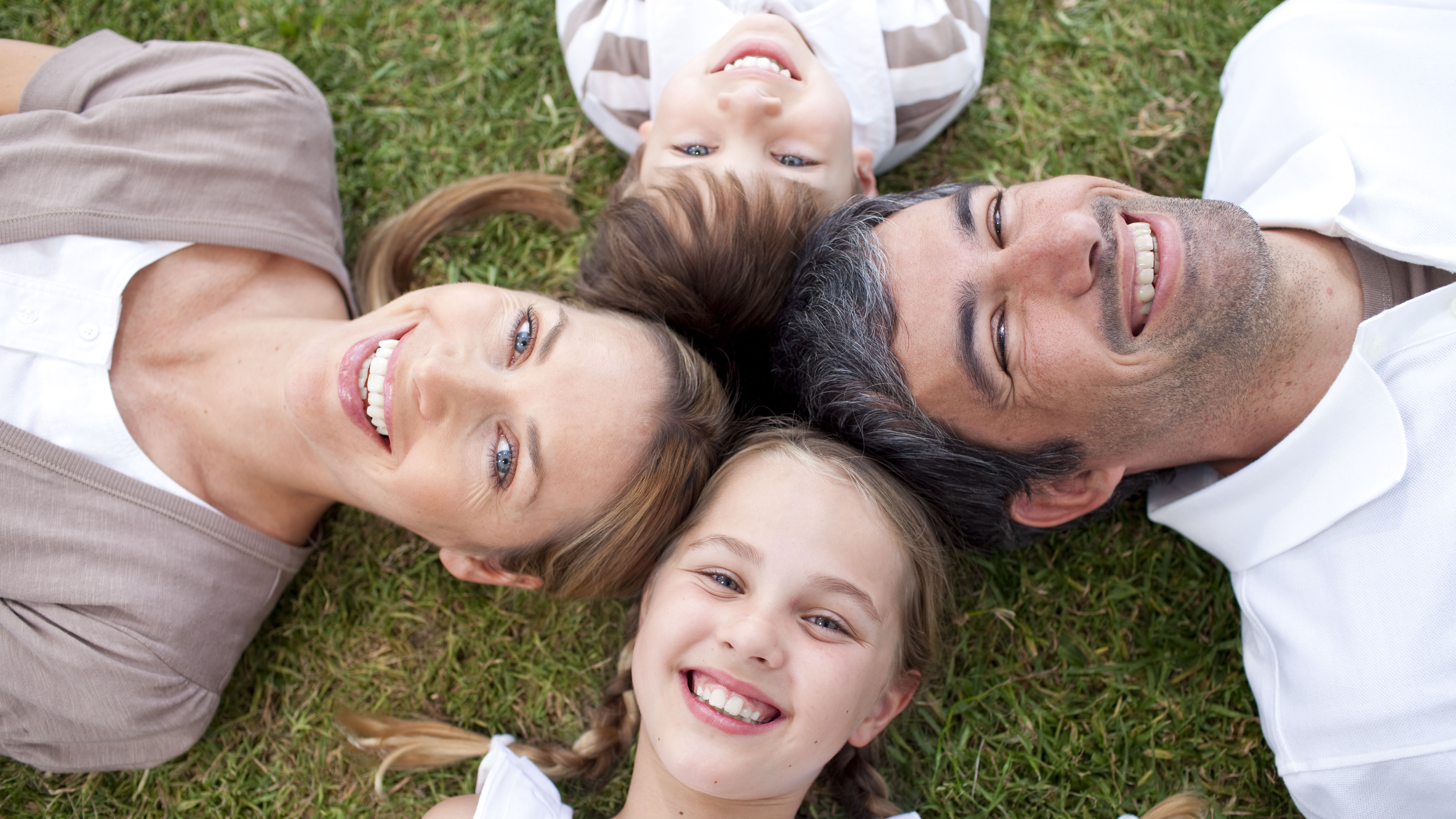 Люди лежали семьями. Семья улыбка. Семья улыбается. Красивая улыбка семья. Фото счастливой семьи лежащей на траве.